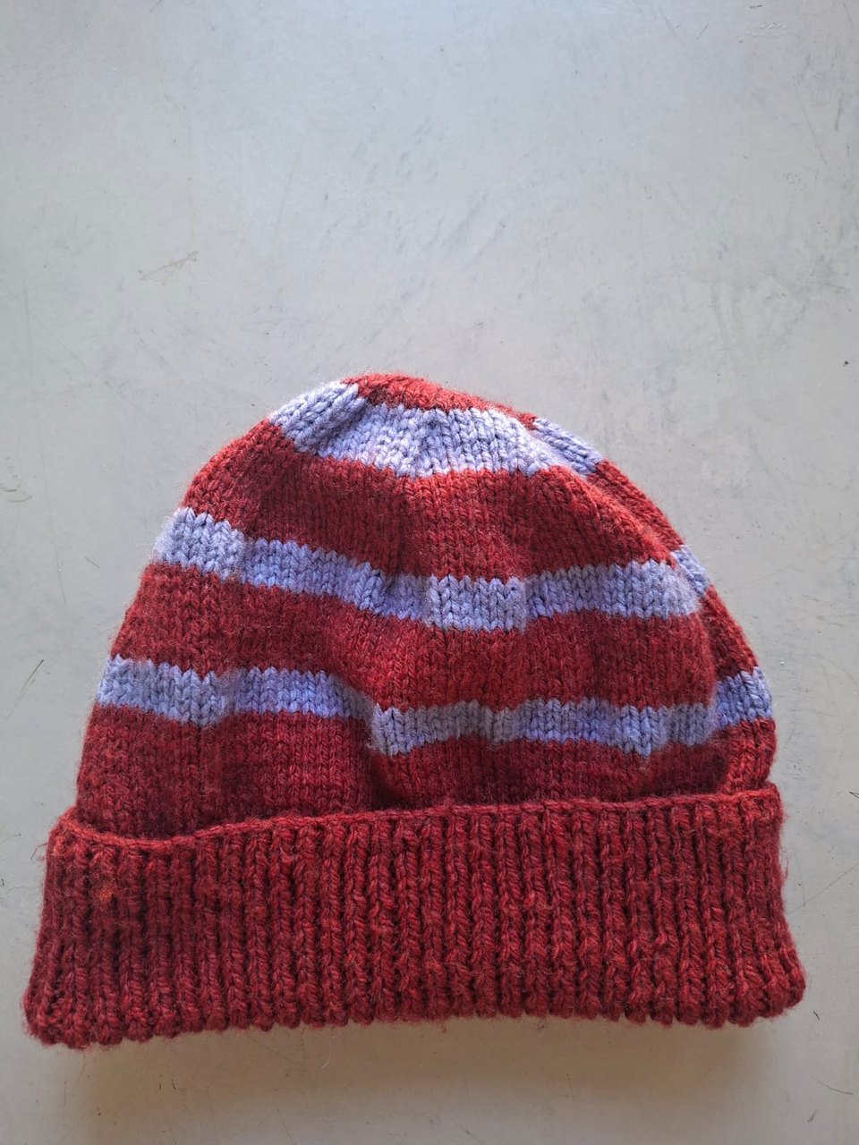 Red beanie with periwinkle blue stripes, hand-knitted at Kranshoek