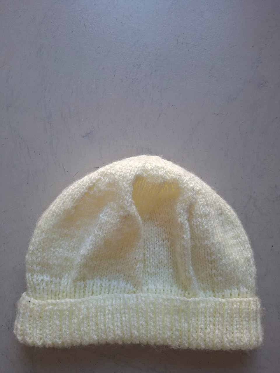 Plain pale cream beanie with a folded cuff, hand-knitted at Kranshoek