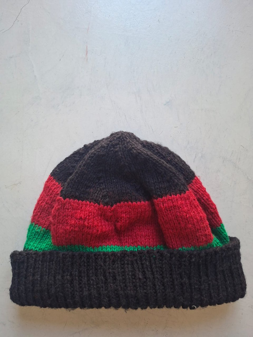 Charcoal beanie with red and green bands, hand-knitted at Kranshoek