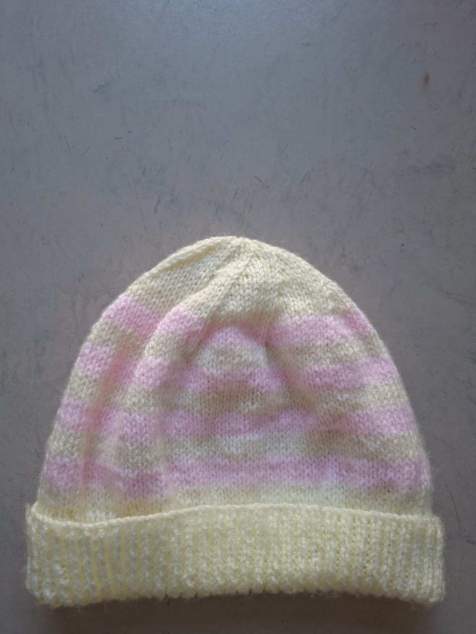 Cream beanie with a soft pink blush through the crown, hand-knitted at Kranshoek