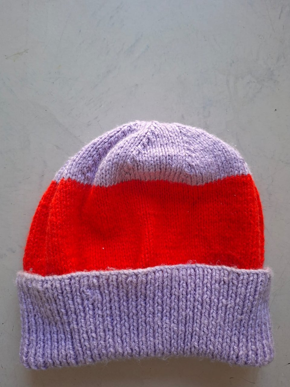 Lilac beanie with a wide red band, hand-knitted at Kranshoek