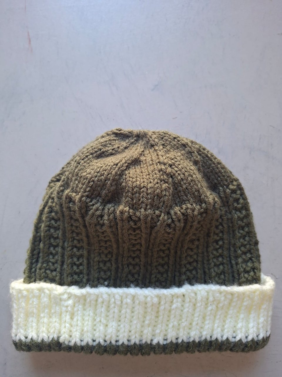 Olive green cable knit beanie with a cream cuff, hand-knitted at Kranshoek