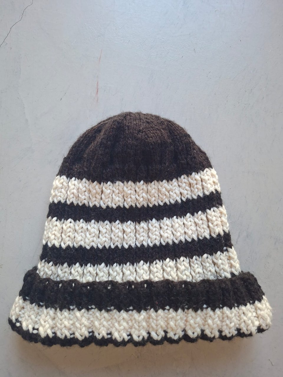 Dark brown beanie with cream textured stripes and a scalloped edge, hand-knitted at Kranshoek