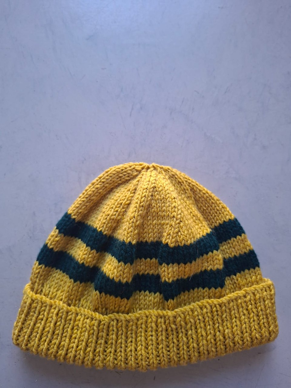 Mustard gold beanie with dark teal stripes, hand-knitted at Kranshoek